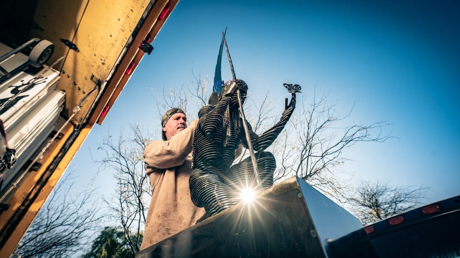 John setting a sculpture against a winter sky