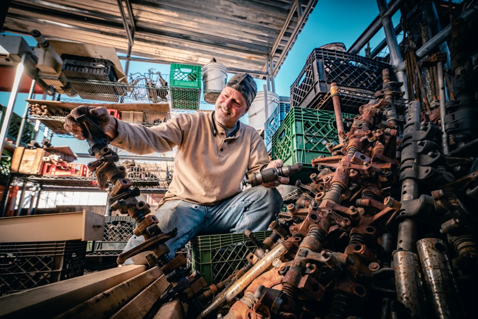 John among crates of recycled engine and bicycle parts outside his studio
